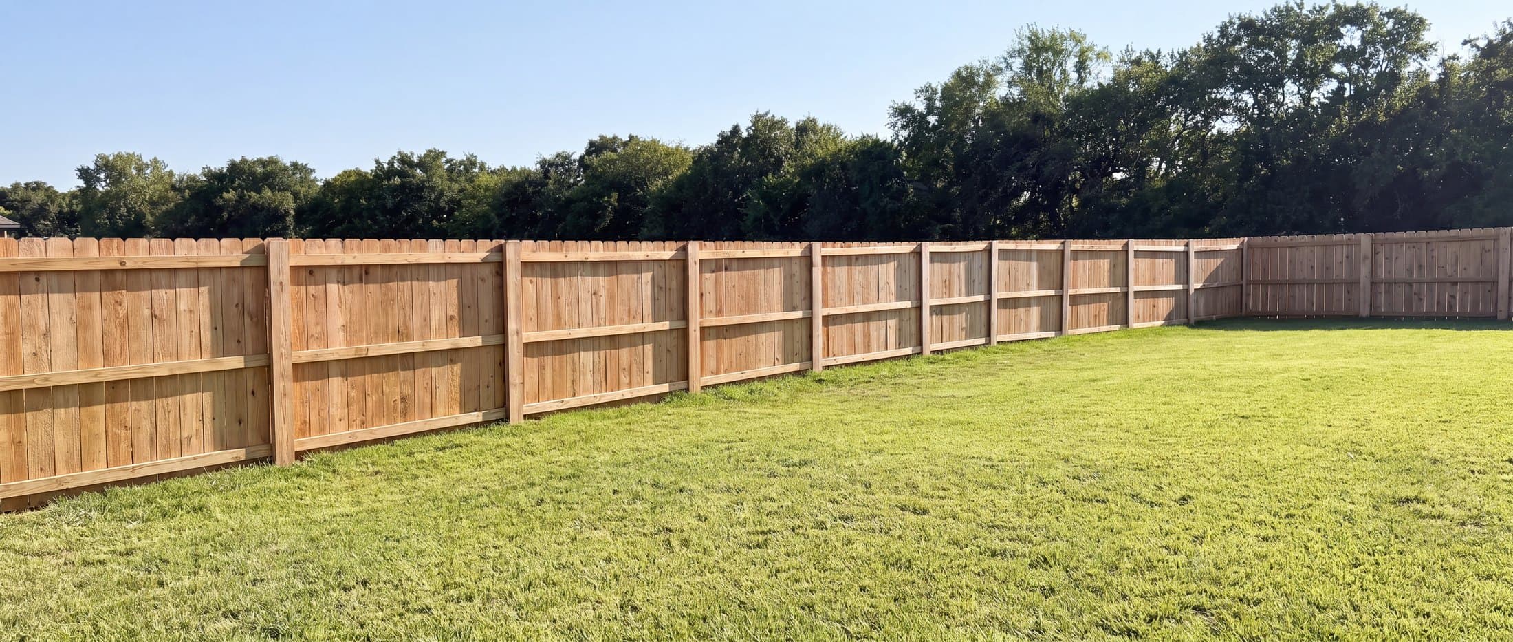 Cedar privacy fence along an open lawn and treeline